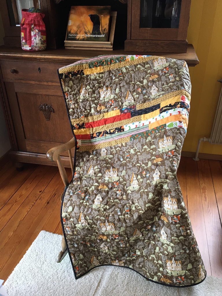 Grandpa Fritz’s Quilt: Strips of memory fabrics between large pieces of fabric with a Black Forest motif. Machine pieced, quilted on the longarm. I finished sewing on the binding during a Black Forest vacation with the whole extended family.