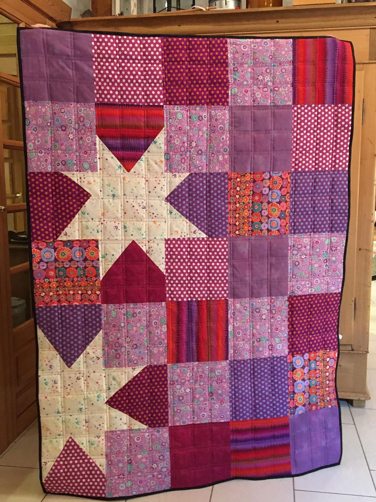 The quilt A Star is born in purple, pink and cream with one large star, quilted in a grid of straight lines.