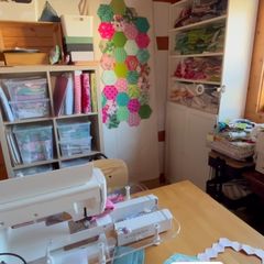 A look into the sewing room: sewing machine, shelves of fabric and a wall of hexagons.