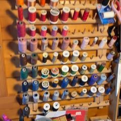 Thread spools in many colors on a wall rack.