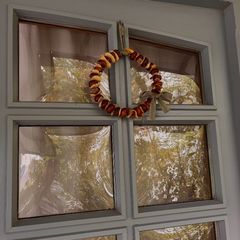 A chestnut wreath with a bow hangs on a glass door.